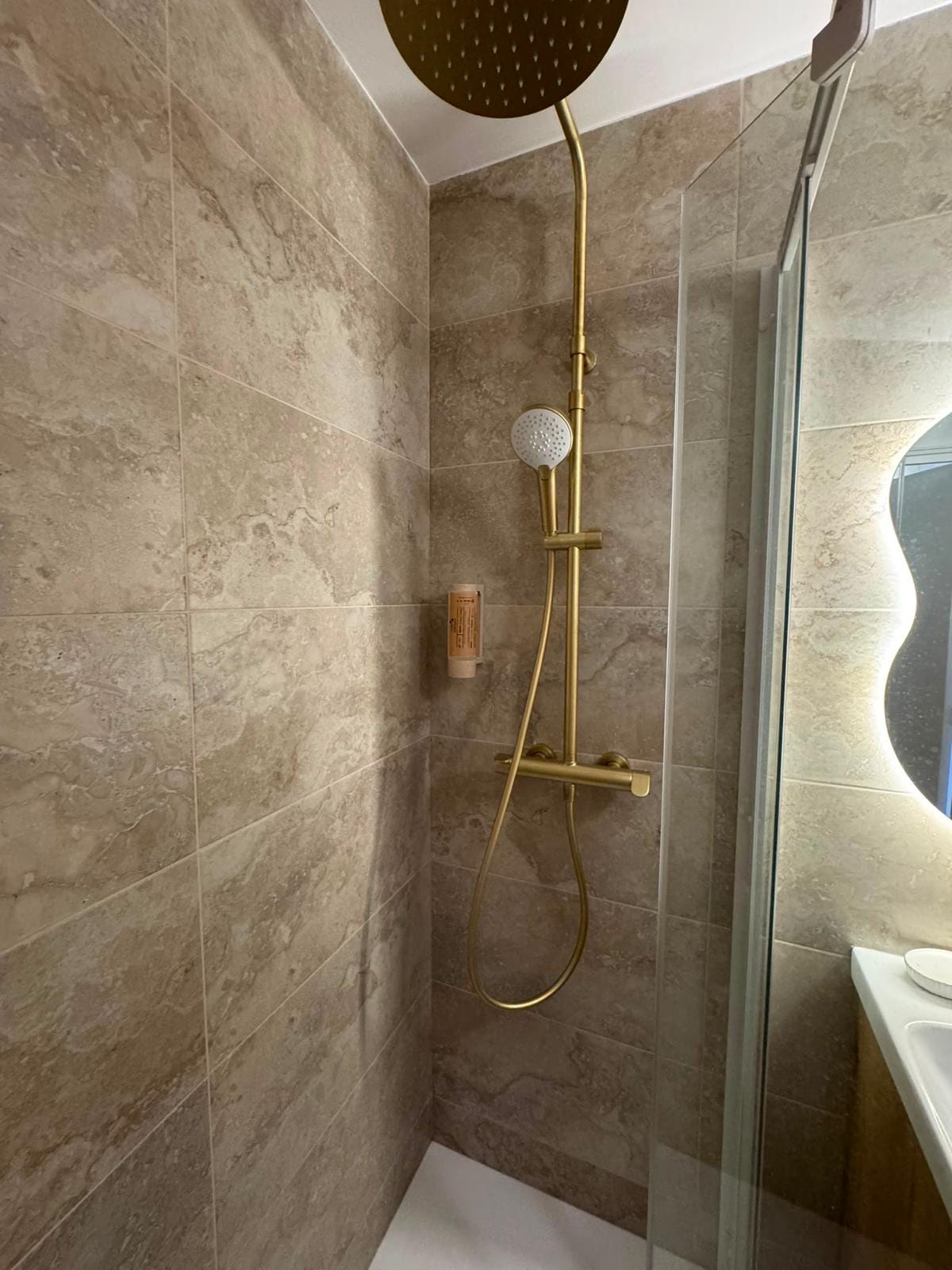 Salle de bains rénovée : douche à l’italienne et robinetterie dorée
